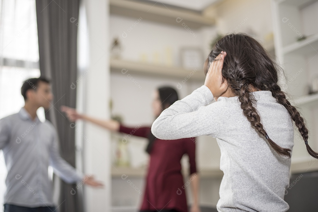 Na visão de trás, a garotinha coloca as mãos nos ouvidos porque não quer ouvir a briga do pai e da mãe. ouvidos fechados, cena dramática familiar, questões de pais, conceito de problema social e de pais.