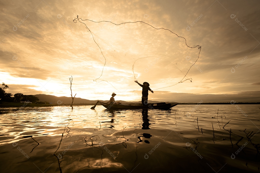 Pescador de silhueta usando rede no barco com luz solar na Tailândia, conceito de natureza e cultura.