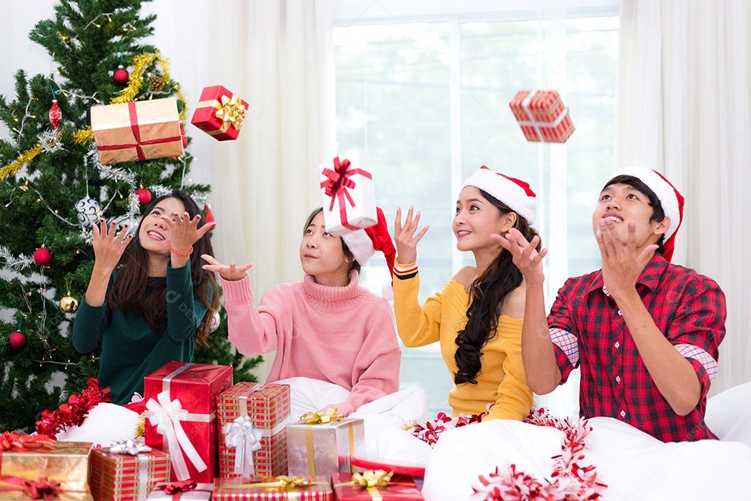 Grupo de jovens asiáticos jogando caixa de presente para o ar com fundo de árvore de Natal. Conceito de férias e festivais.