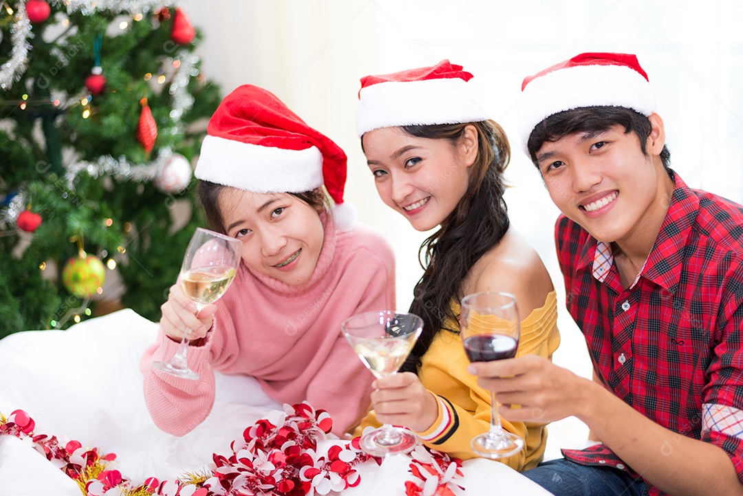 Grupo de jovens asiáticos comemorando a festa de ano novo em casa com copos de vinho.