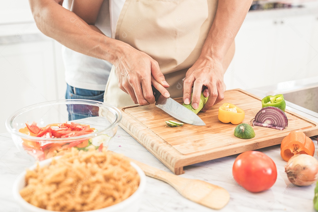 Mãos de casal ou amantes cozinhando e cortando legumes com faca juntos. Homem ensinando mulher a cozinhar. Felicidade no conceito de férias e lua de mel.