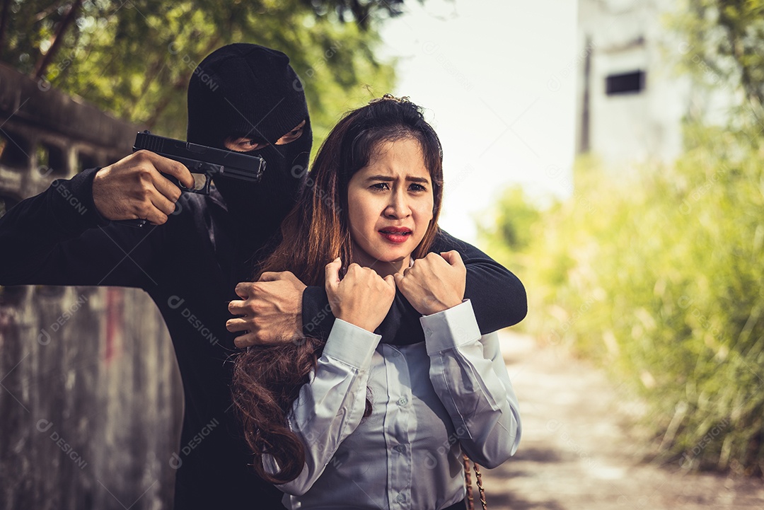 Sequestrador ou ladrão força refém de faca a tirar a roupa ou roubar seu dinheiro na estrada ao ar livre.