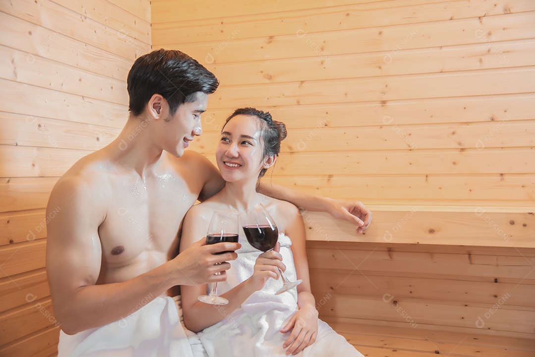 Amantes asiáticos bebendo vinho na sala de sauna, tratamento térmico com vapor, conceito de férias e relaxamento.
