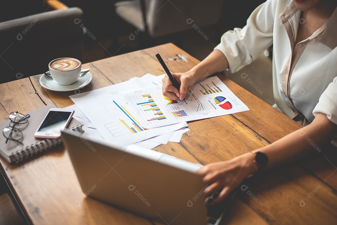 Close-up da mulher de negócios trabalhando com documentos e laptop no escritório.