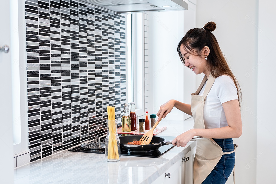 Mulher asiática cozinhando espaguete na cozinha alegremente. Conceito de pessoas e estilos de vida.