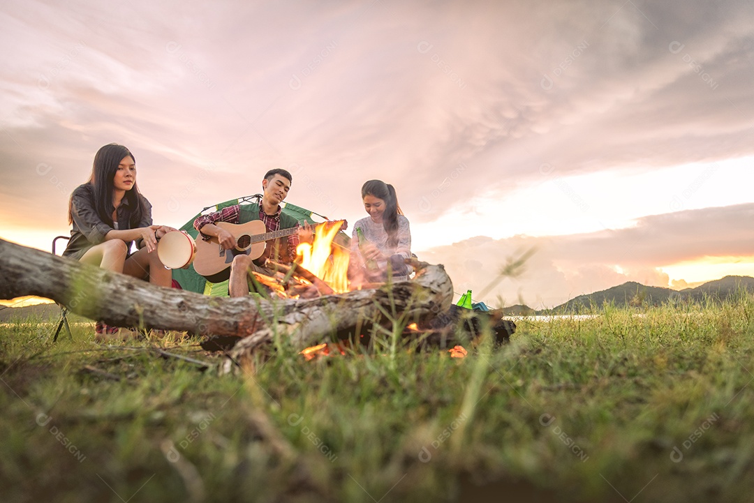 Grupo de viajantes acampando e fazendo piquenique e tocando música juntos. Fundo de montanha e lago.
