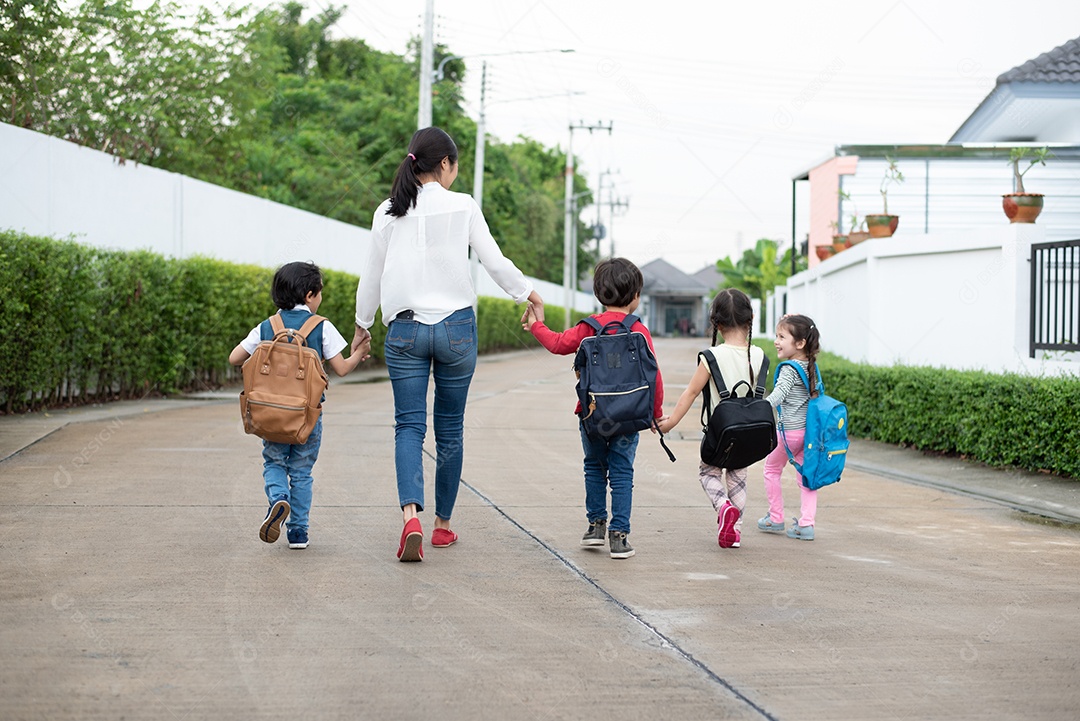 Grupo de alunos da pré-escola e professores de mãos dadas e caminhando para casa. Mãe traz seus filhos para a escola juntos.