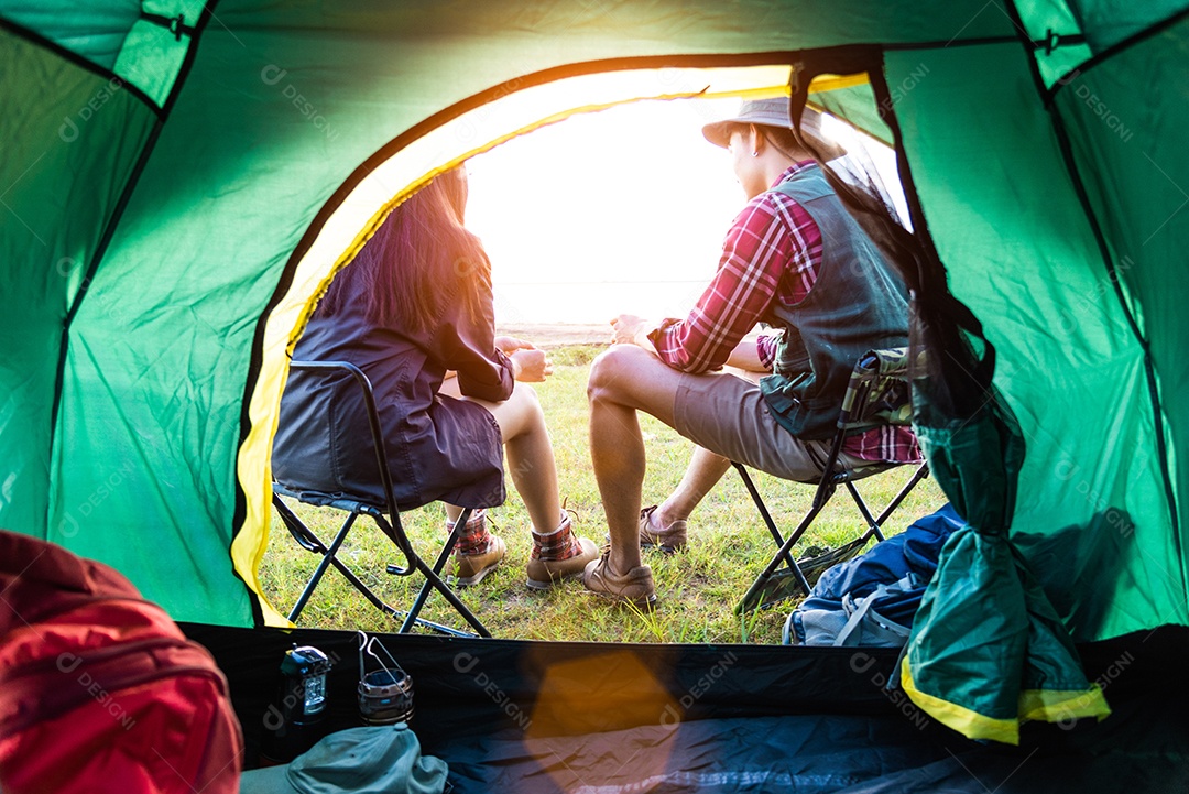 Campistas masculinos e femininos conversando na frente da barraca de acampamento.