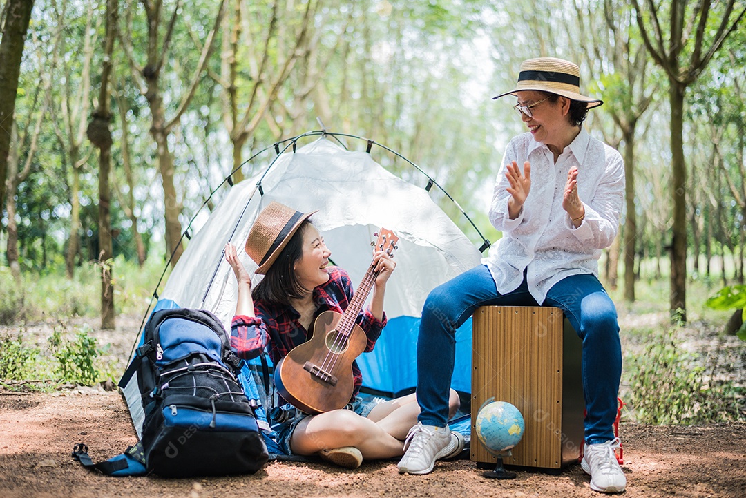 Menina asiática e mãe tocando música na floresta ao ar livre. Conceito de pessoas e estilos de vida. Tema natureza e viagens.