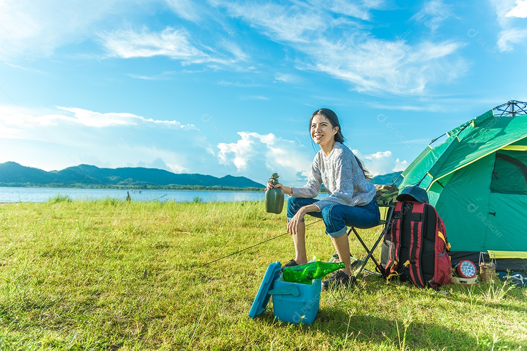Mulher feliz bebendo álcool enquanto acampava no prado. Conceito de pessoas e estilos de vida. Tema de viagem e aventura. Retrato de turista feminino