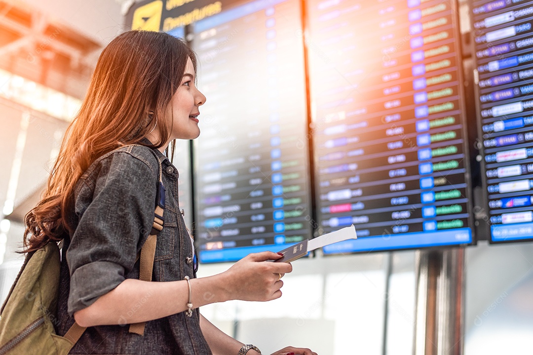 Beleza turista asiática olhando para horários de voo para verificar o tempo de decolagem.