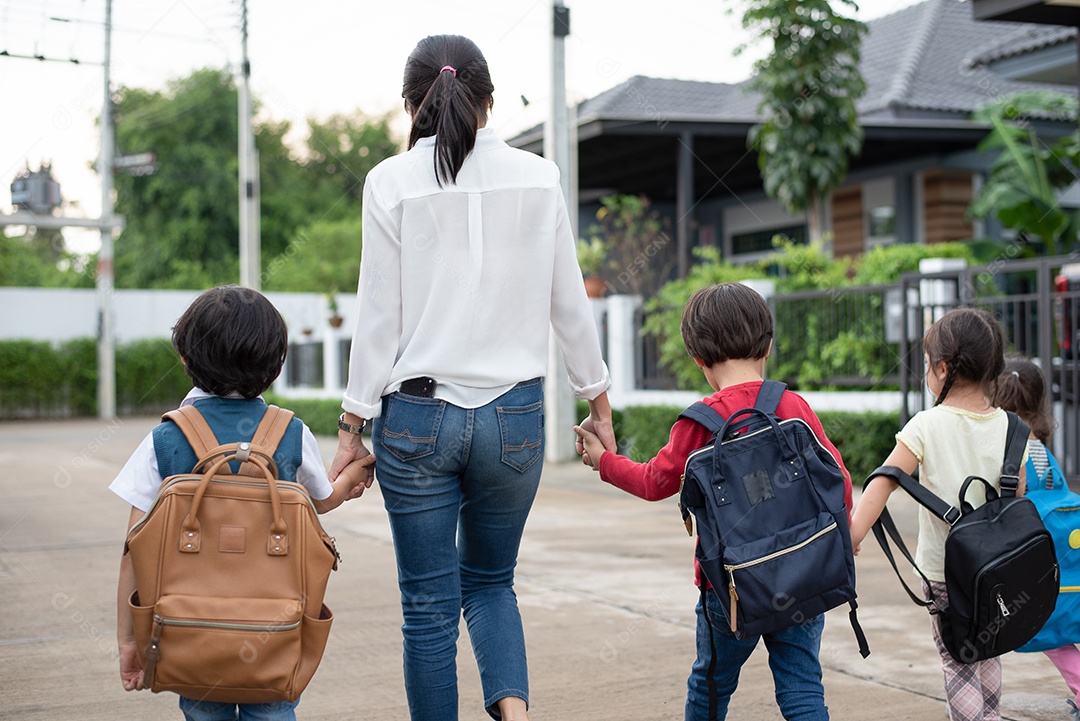 Grupo de alunos da pré-escola e professores de mãos dadas e caminhando para casa. Mãe traz seus filhos para a escola juntos.