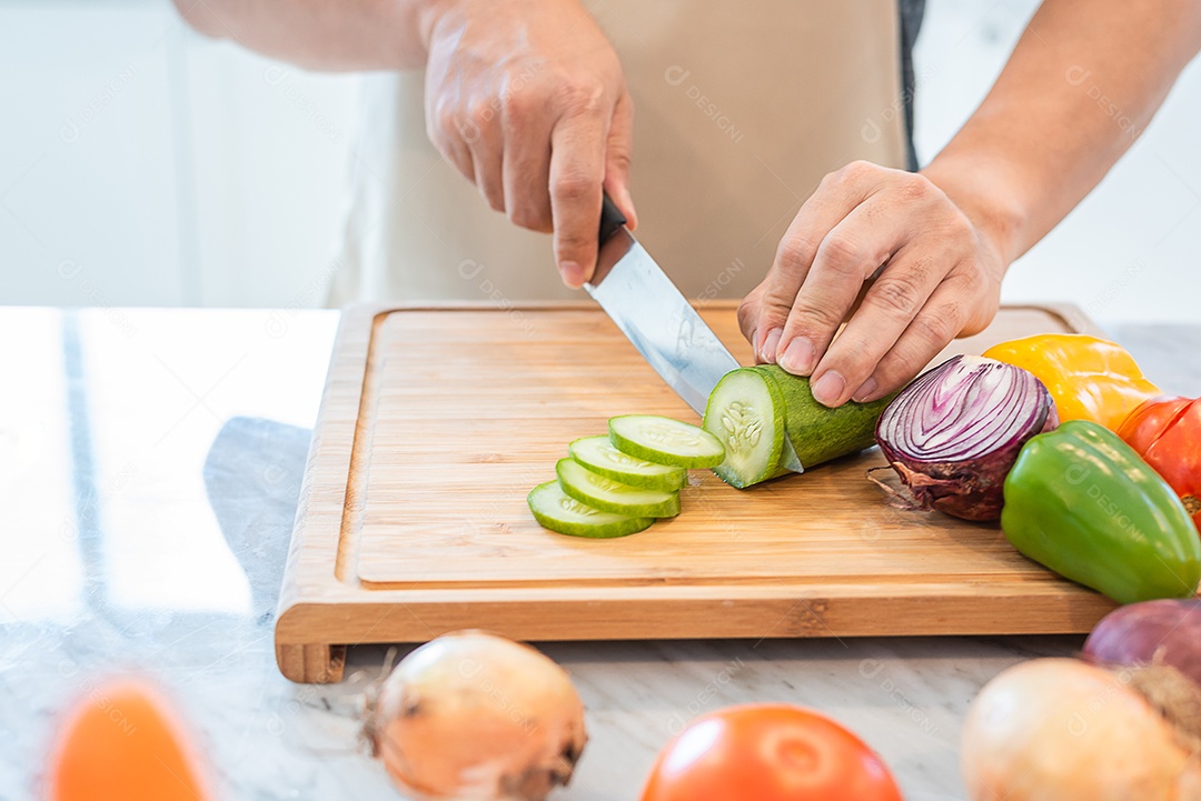 Feche a mão do homem cozinhando e cortando vegetais na cozinha para preparar o jantar com sua esposa ao voltar para casa.