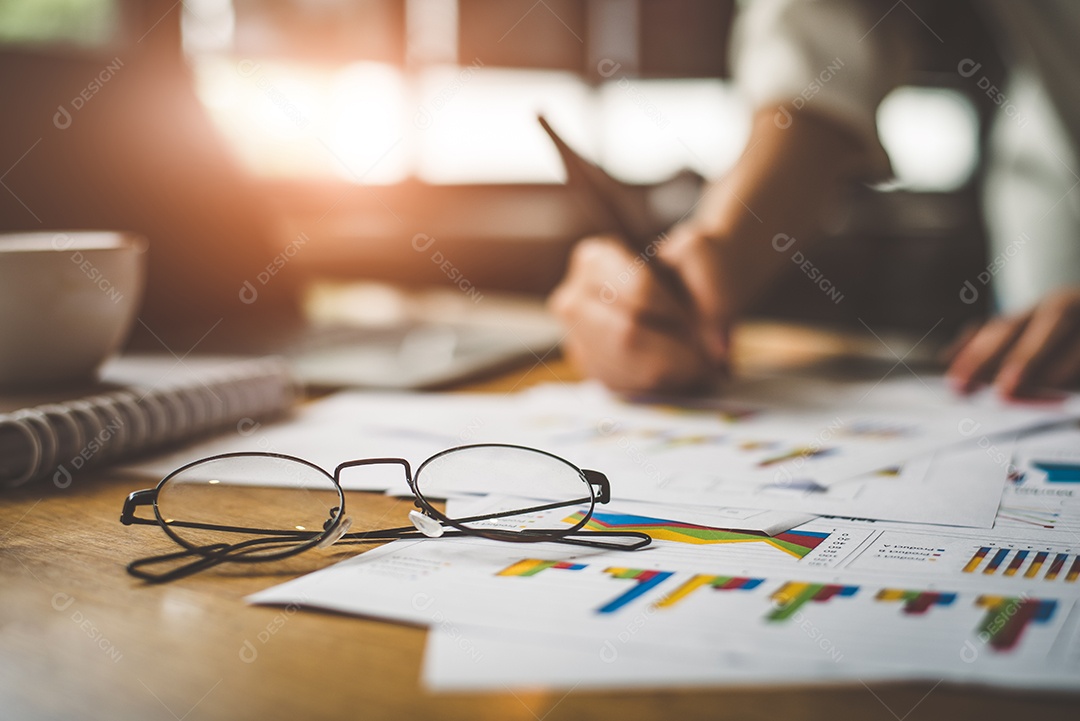 Close-up de óculos com empresária escrevendo dados de relatório de resumo em segundo plano.