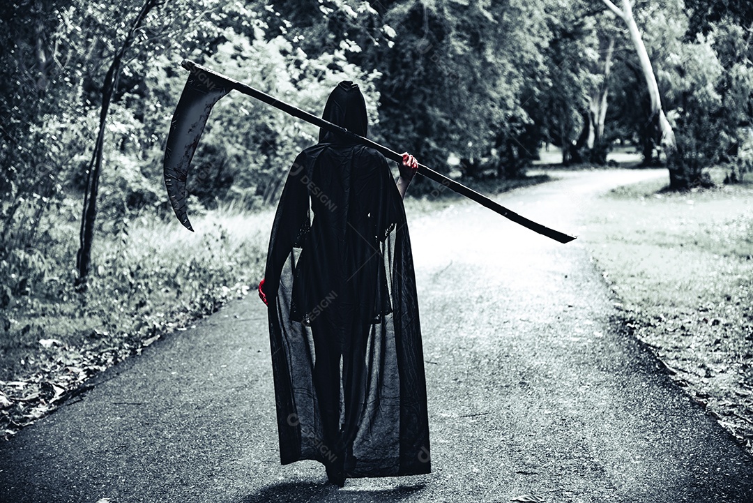 Vista traseira da bruxa demônio com ceifador e sangue vermelho nas mãos caminhando ao longo do fundo da estrada.