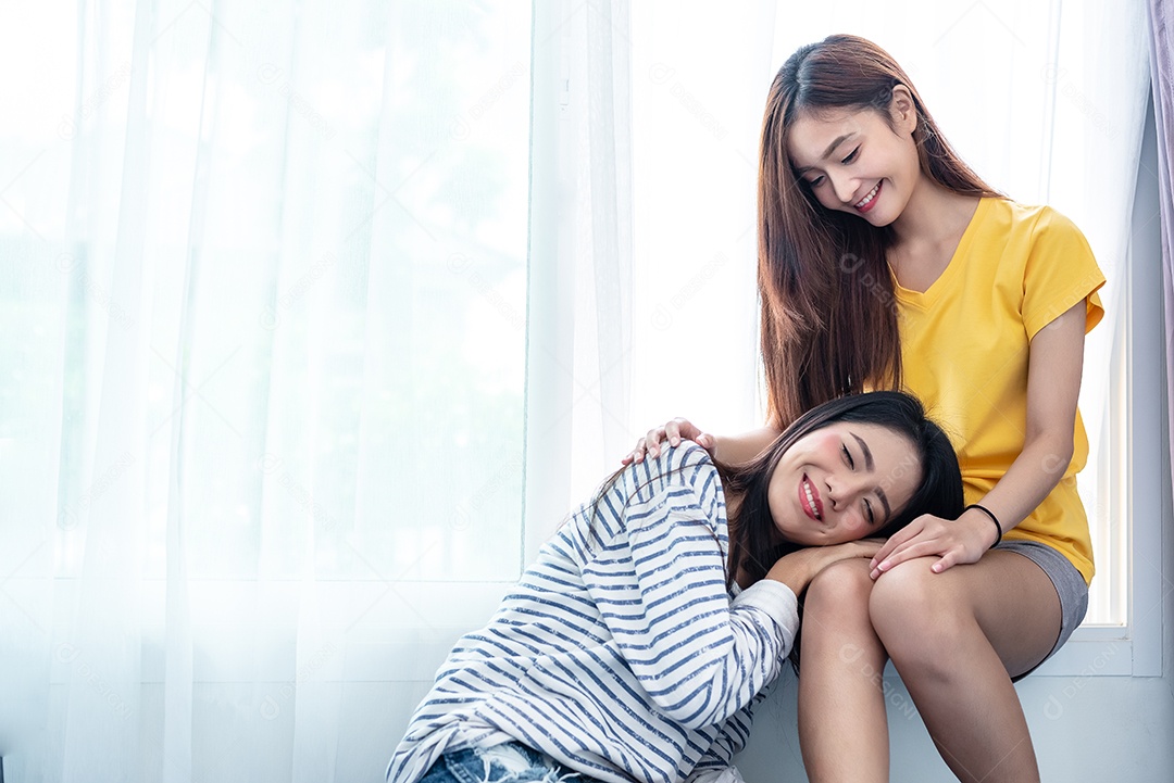 Casal asiático cuida junto perto da janela branca com sóis suaves.