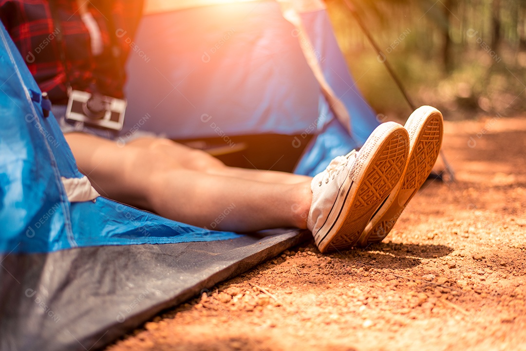 Feche os pés de estiramento de mulher com sapato com fundo de natureza. Mulher turista descansando na barraca de acampamento.