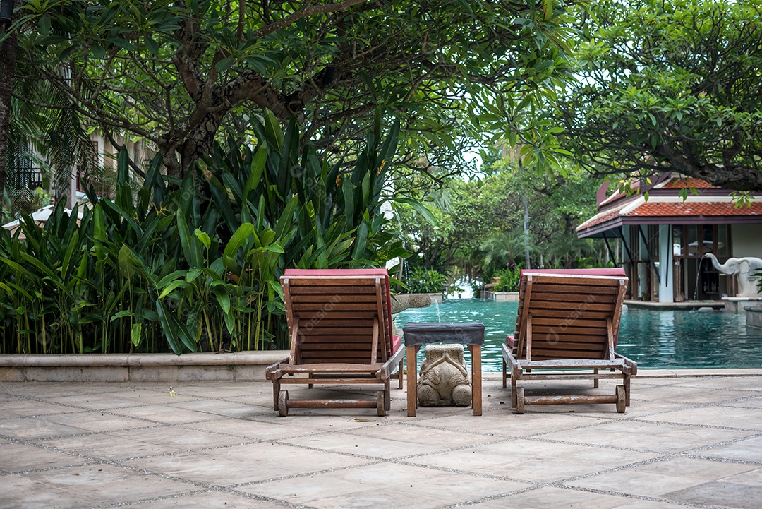 Bela espreguiçadeira perto da piscina. Conceito de férias e relaxamento. Estilos de vida e tema interior. Tema de verão e primavera. Vista traseira.