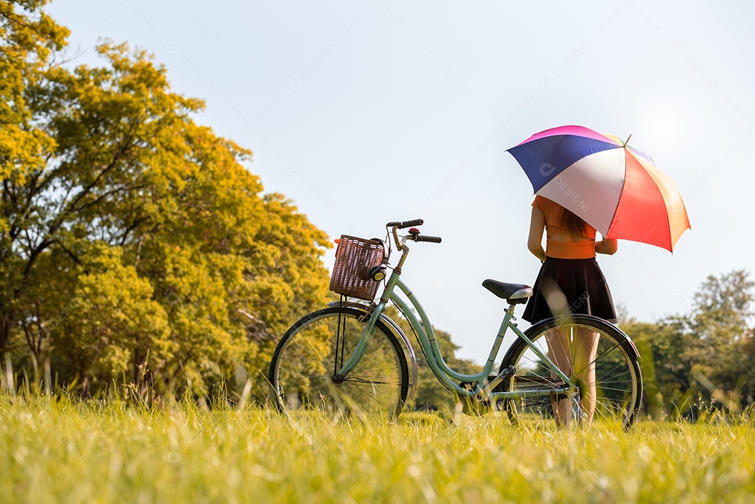 Mulher com guarda-chuva colrful e bicicleta no parque. Pessoas e conceito de relaxamento. Tema da temporada e outono.