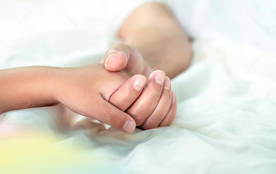 Feche a mãe segurando a mão do bebê na cama branca, ligação de amor, encorajamento e calor cuidando um do outro na família, conceito de família