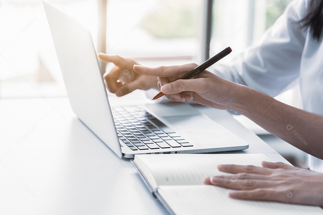 Close-up de duas empresárias usando laptop e escrevendo no caderno pela manhã. Conceito de negócios e financeiro.