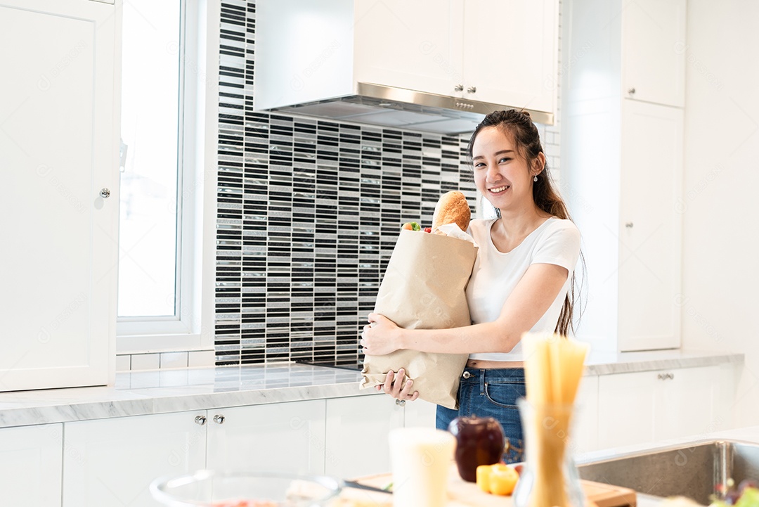 Mulher de beleza asiática segurando saco de ingredientes para cozinhar depois.