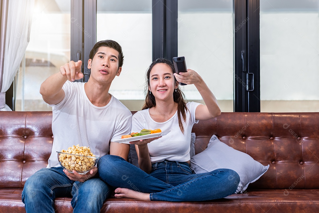 Casais asiáticos assistindo televisão juntos no sofá em sua casa. Conceito de pessoas e estilos de vida.