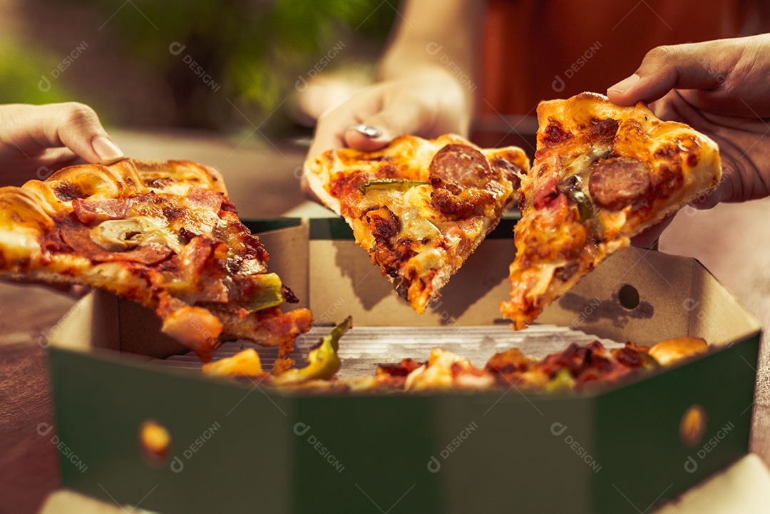 Feche de pizza quente fatiada segurando pelas mãos de pessoas de amizade para festa de comemoração.