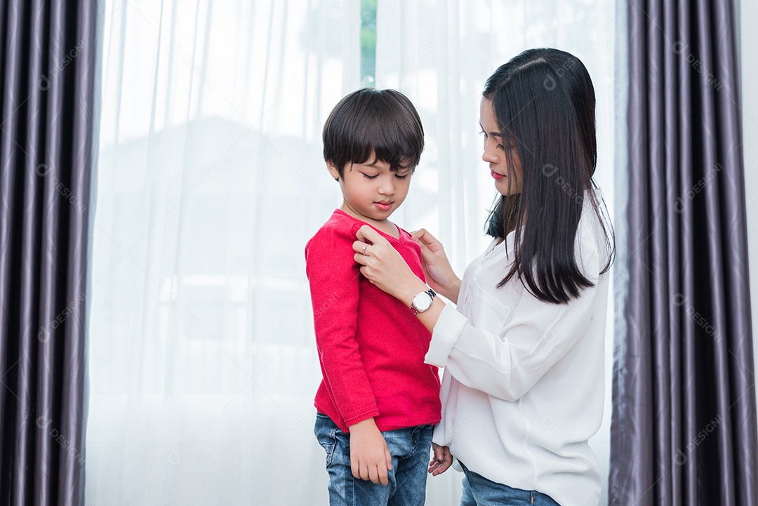 A jovem mãe asiática vestiu a camisa do filho para se preparar para a escola.