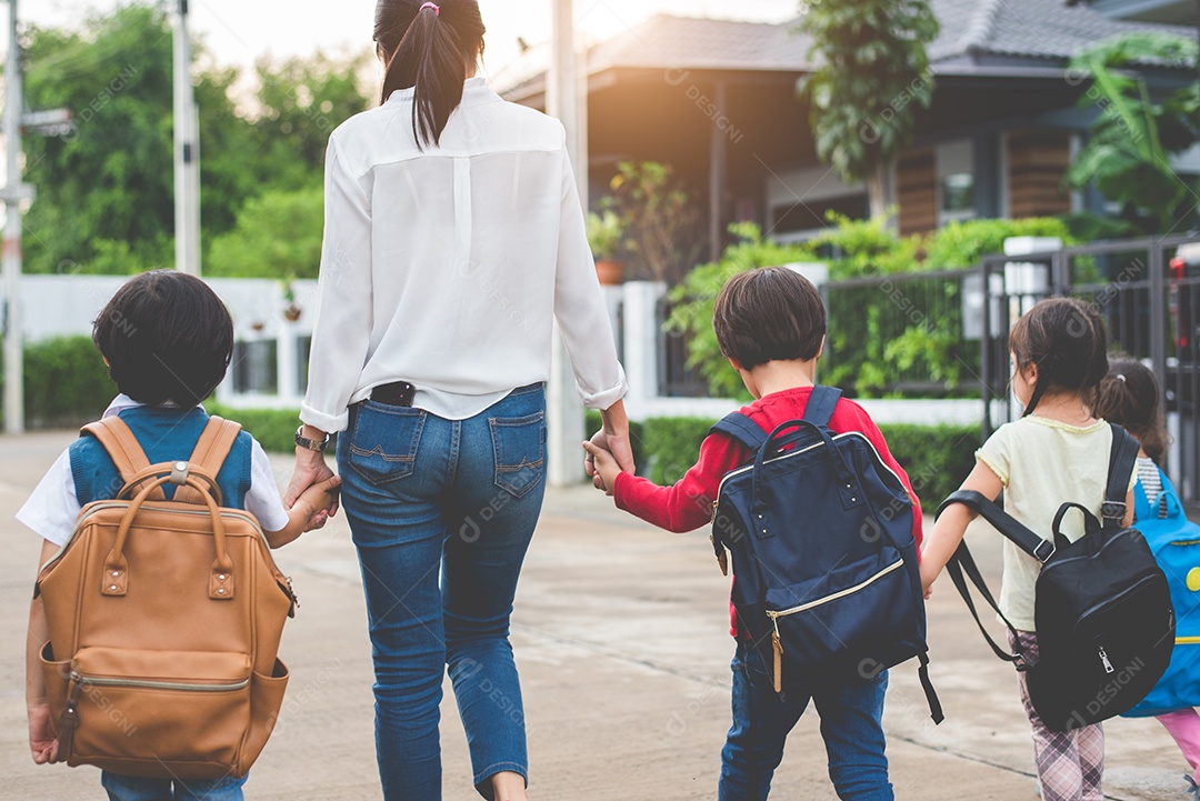 Grupo de mãe e filhos de mãos dadas indo para a escola com mochila.