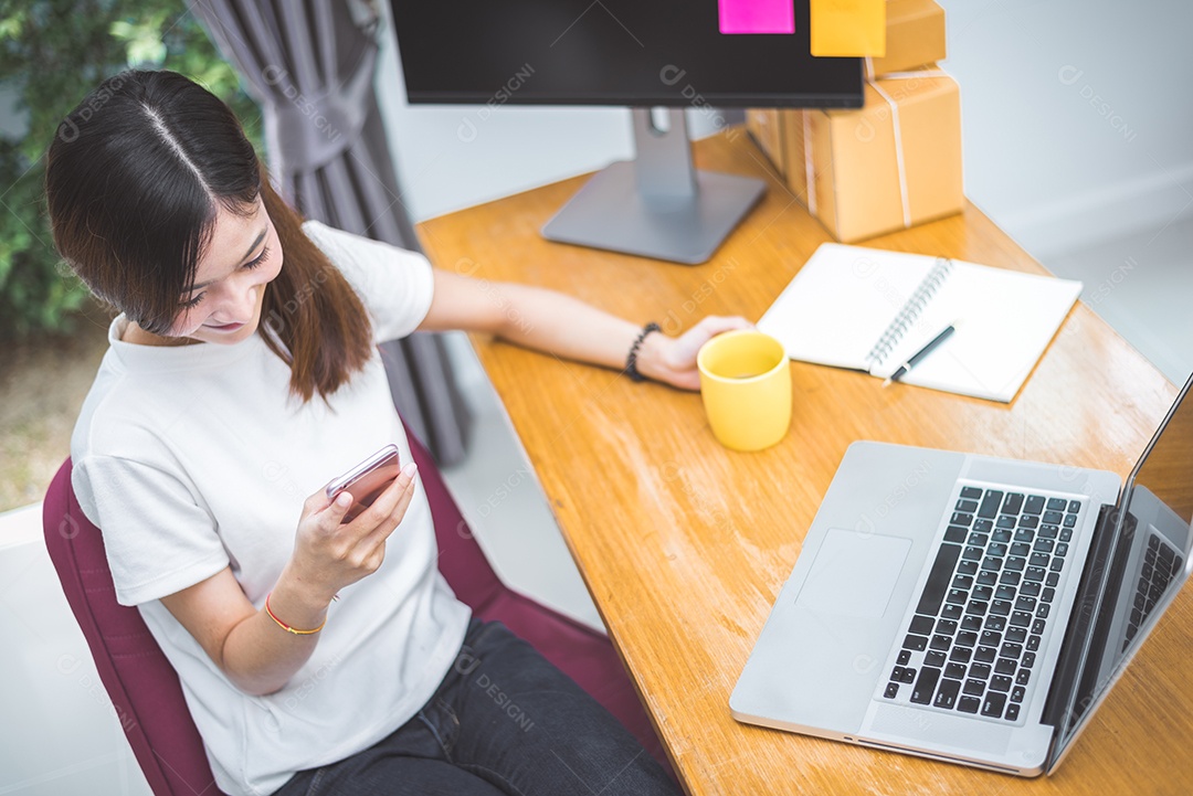 Vista superior da mulher usando telefone celular e laptop como comprador de compras pela tecnologia de internet no escritório.