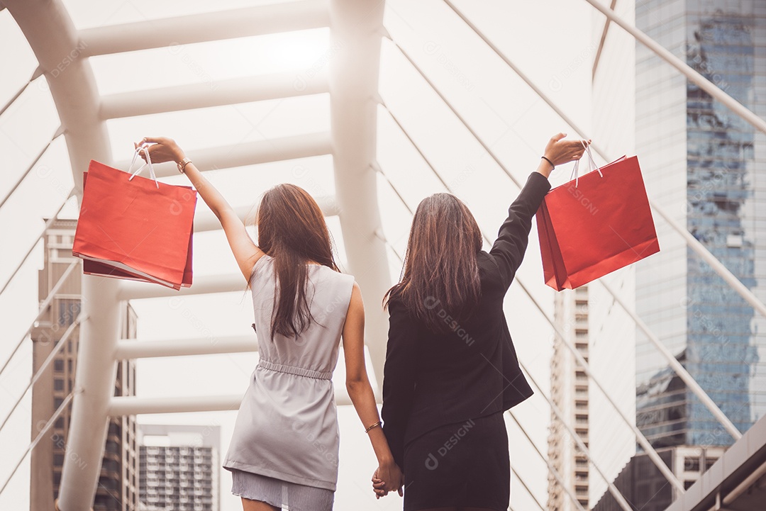 Mulheres de amizade de estilo de vida viciadas em compras segurando uma sacola de compras no shopping center.