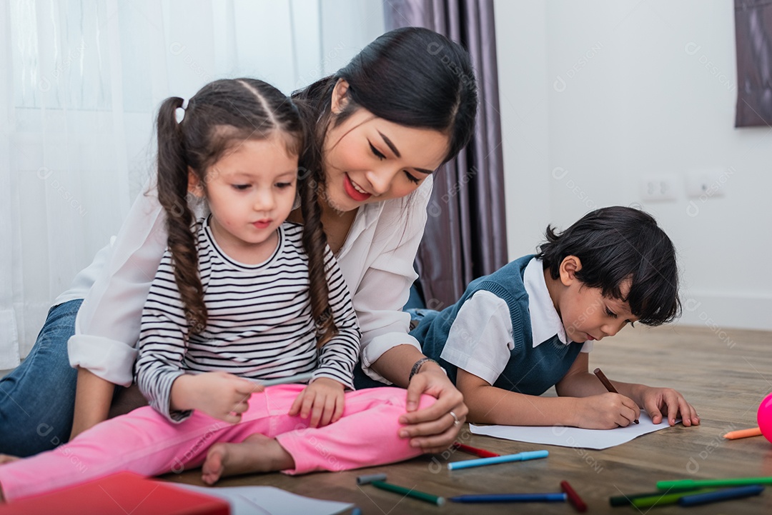 Mãe ensinando crianças na aula de desenho. Filha e filho pintando com giz de cera colorido em casa.