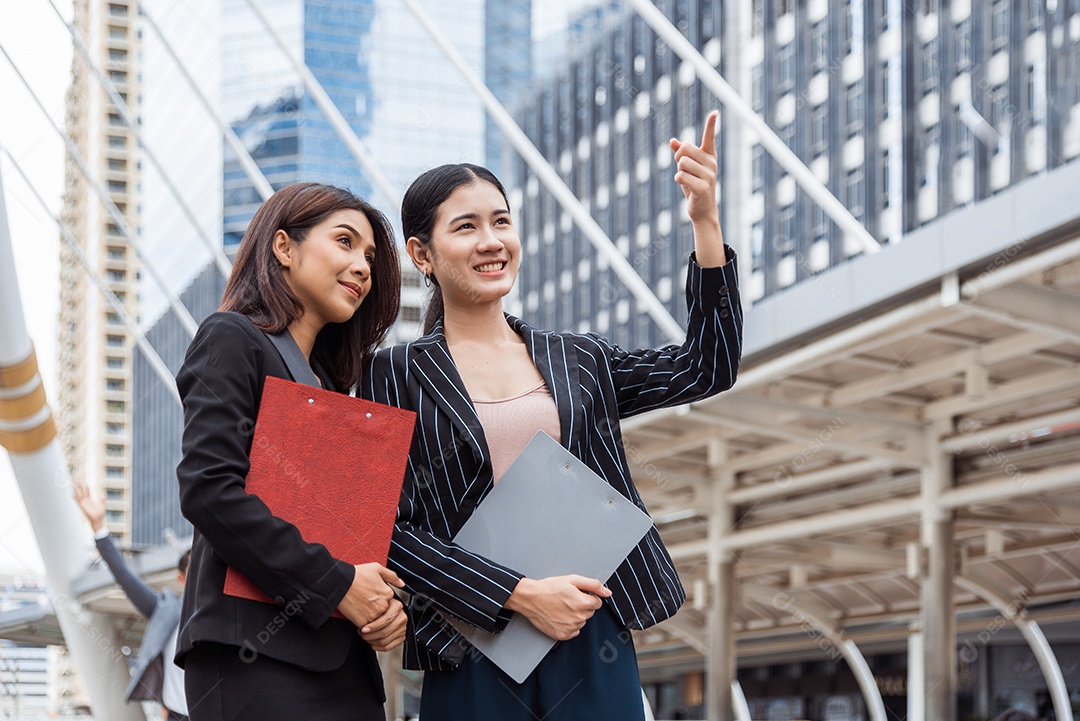 Duas jovens empresárias olhando e apontando para frente para pensar.