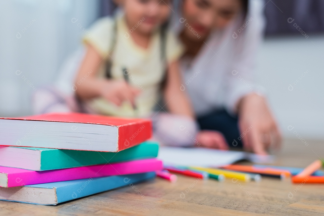 Feche de livros no chão com fundo de mãe e filhos.