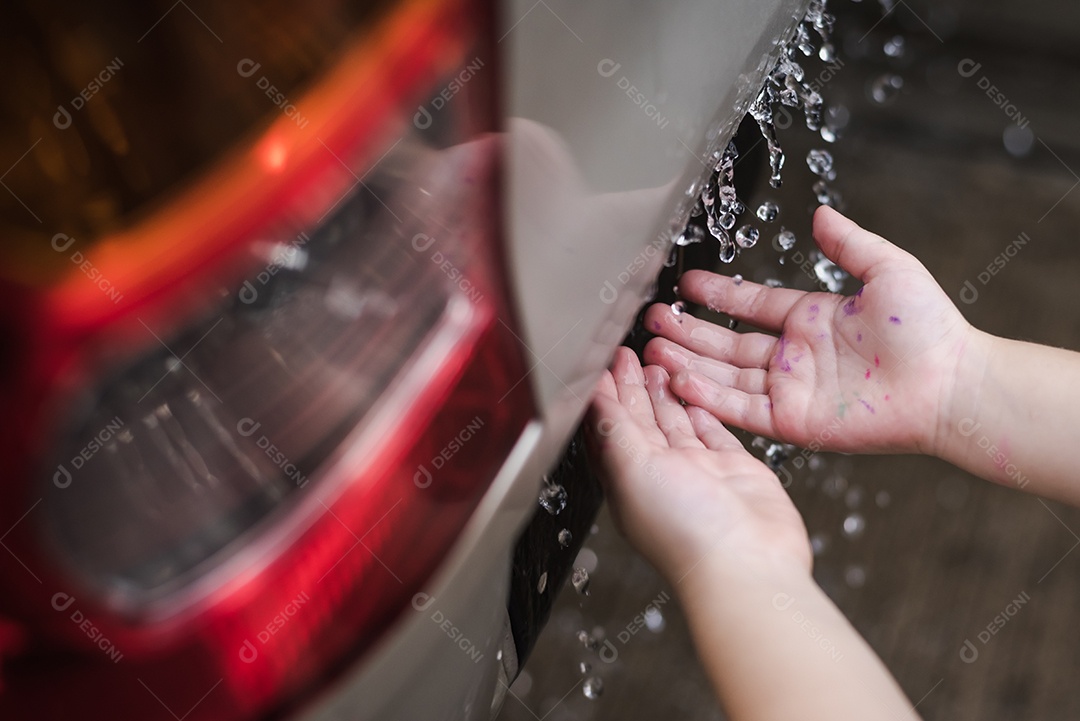 Mãos de crianças brincando com gotas de chuva depois de chover atrás do carro. Conceito de educação e aprendizagem.