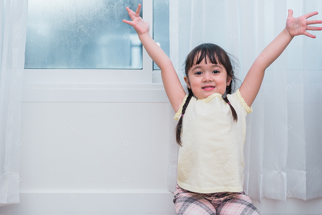 A menina levanta as mãos com humor de gesto feliz. Crianças brincam.