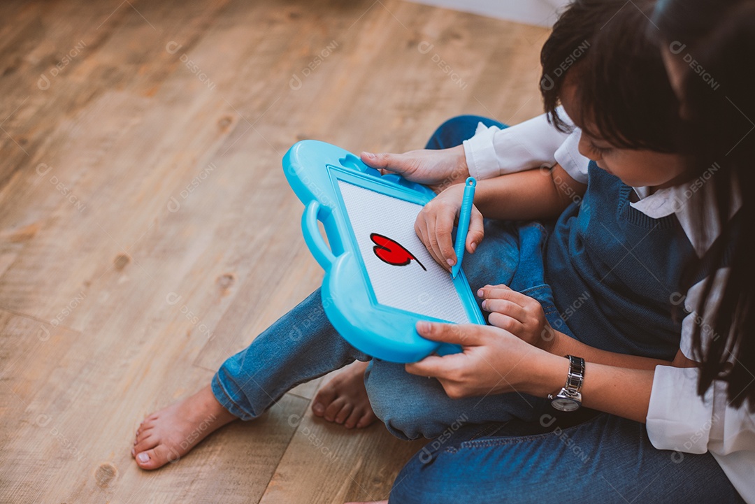Mãe asiática ensinando menino bonito a desenhar coração vermelho a bordo.