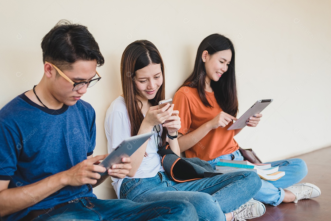Grupo de estudantes universitários asiáticos usando tablet e celular.