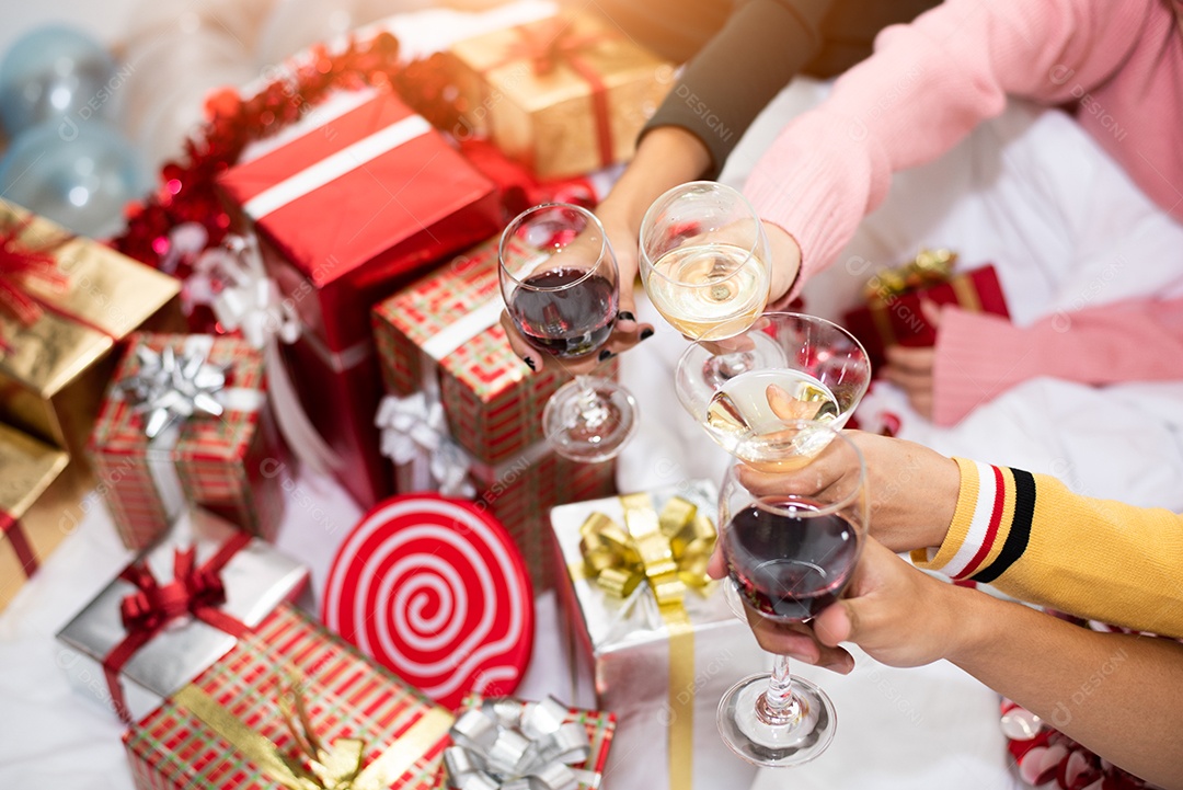 Mãos de pessoas comemorando a festa de ano novo em casa com vinho.