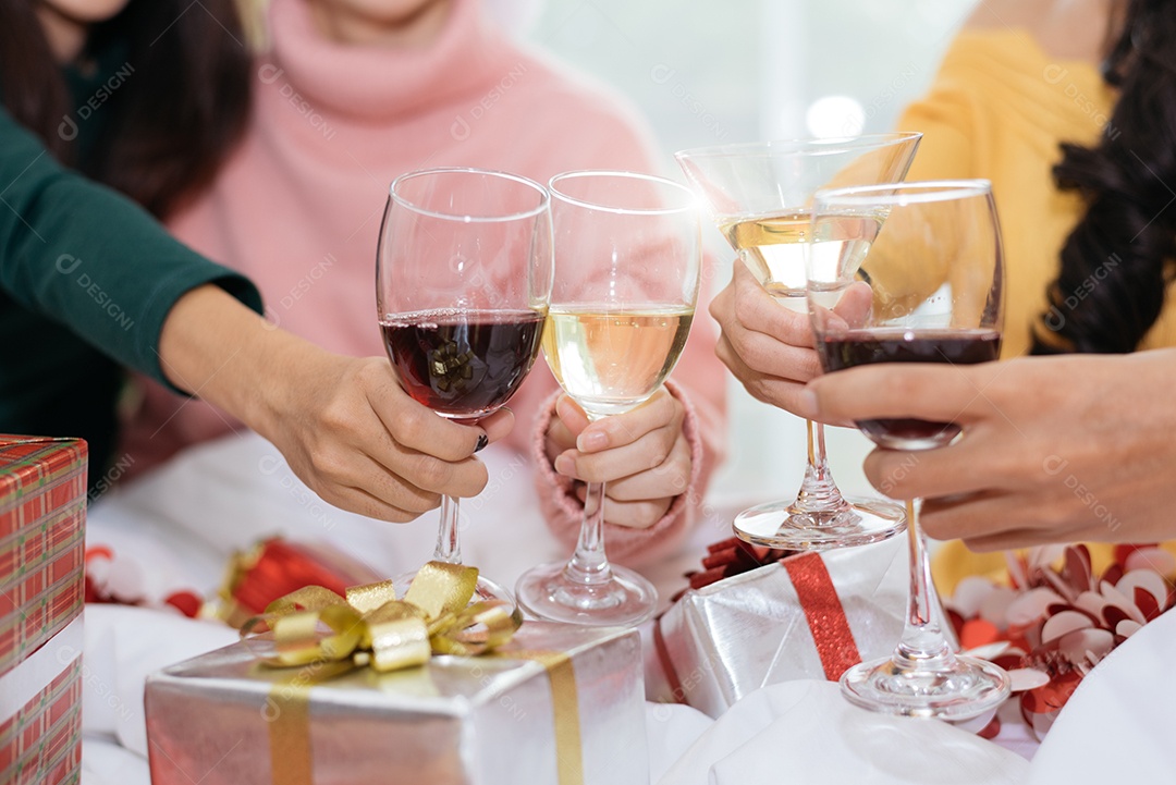 Mãos de pessoas comemorando a festa de ano novo em casa com vinho.