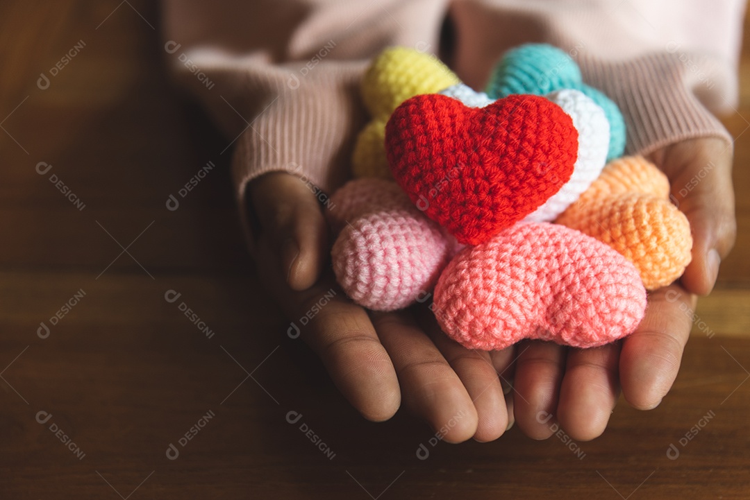 Coração de fio de cores misturadas em dar as mãos. Feche de colorido feito à mão. Conceito de doação de coração. Tema do amor para sempre dos namorados.