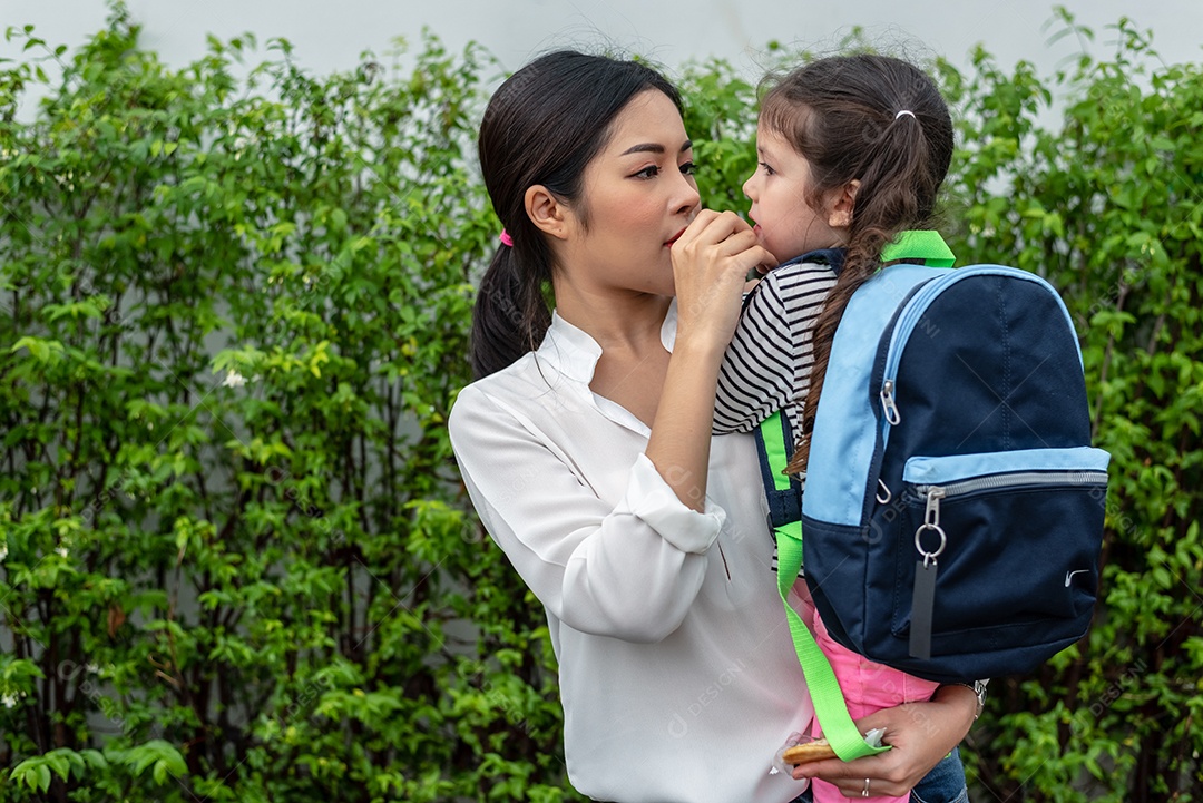 Mãe alimentando a filha com lanche antes de ir para a escola. De volta à escola e ao conceito de educação.