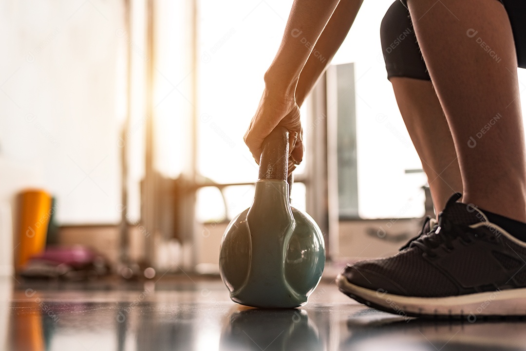 Close-up da mulher levantando kettlebell como halteres em fitness.