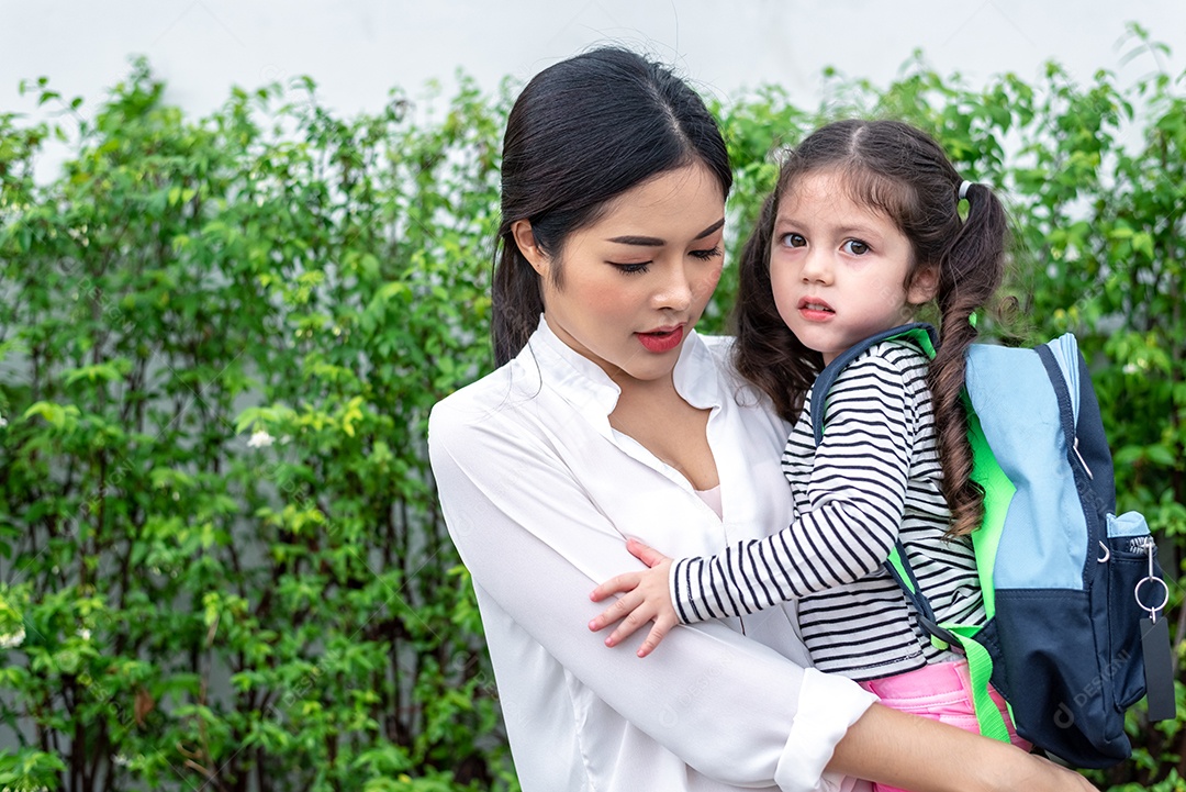 Mãe carregando a filha antes de ir para a escola.