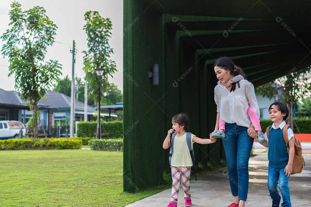 Mãe solteira carregando e brincando com seus filhos no jardim.