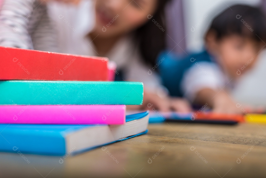 Feche de livros no chão com fundo de mãe e filhos.