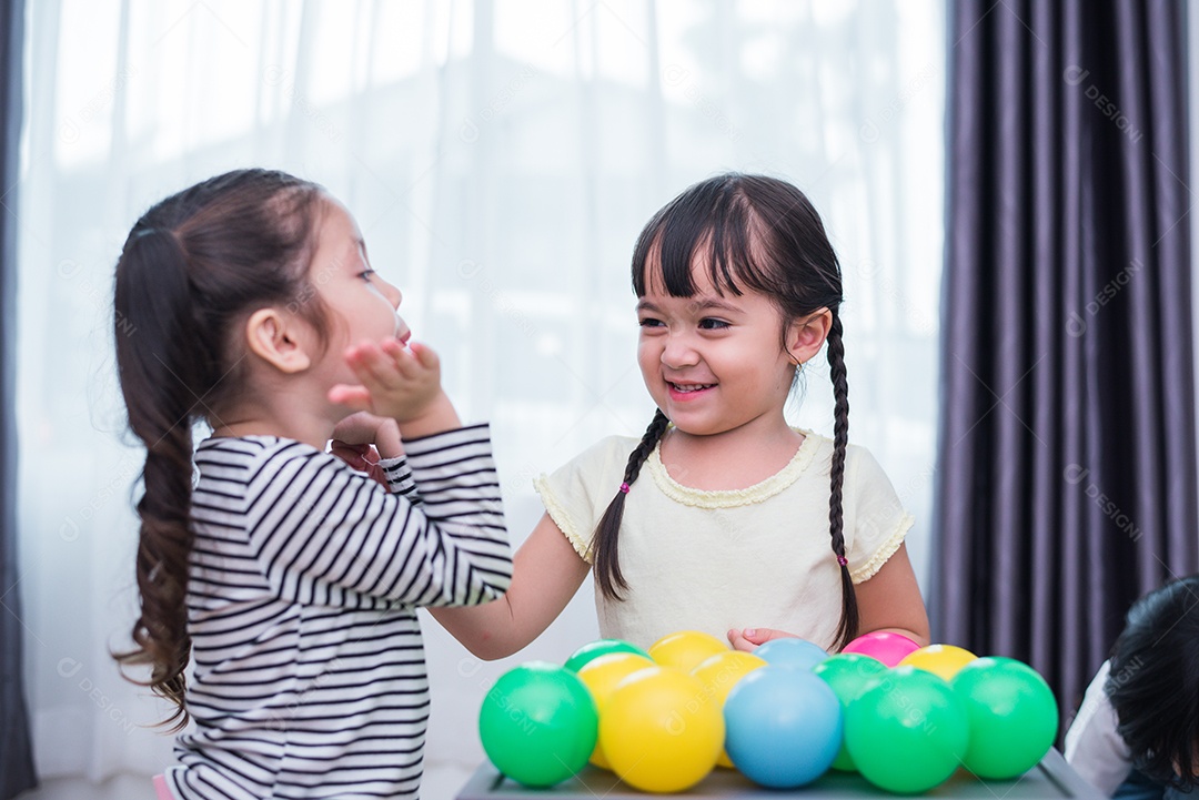Duas meninas jogando pequenas bolas de brinquedo em casa juntos.