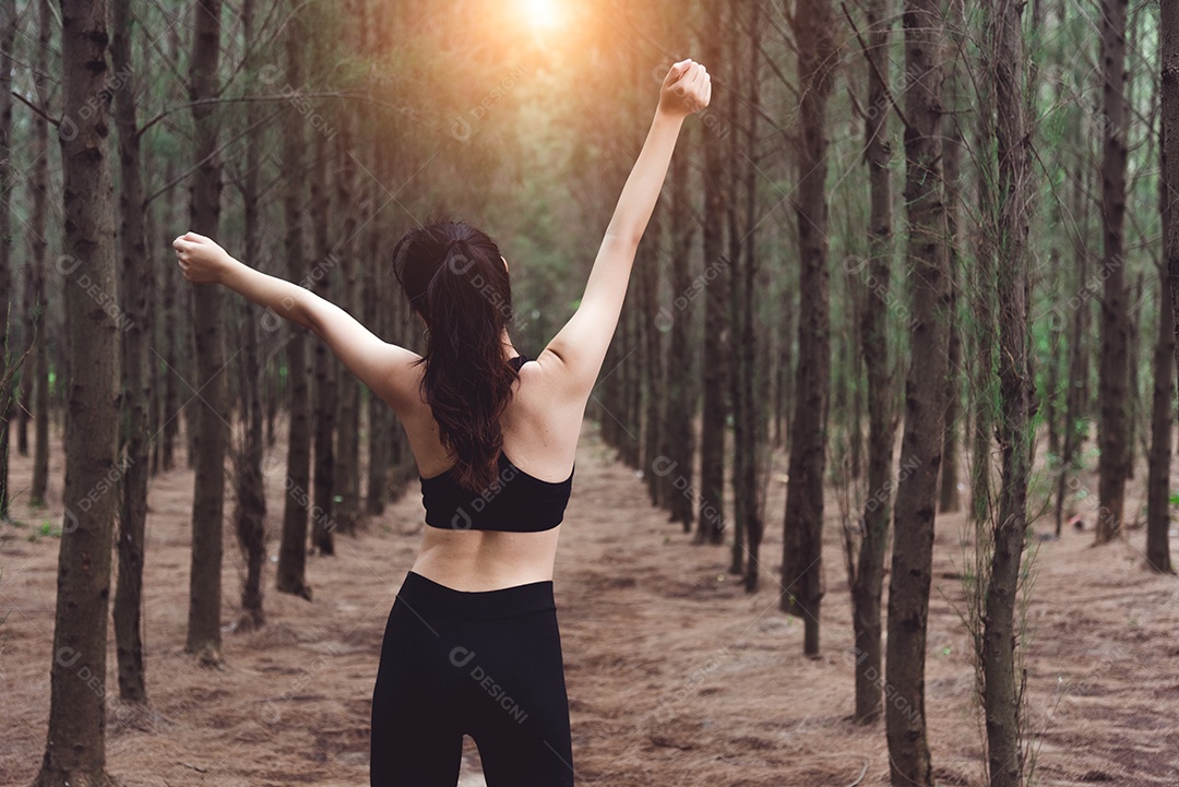 Mulheres esticando os braços e respirando ar fresco no meio do pinheiro.