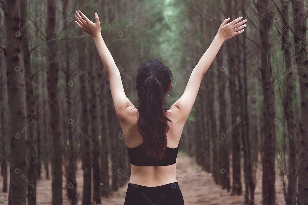 Mulheres esticando os braços e respirando ar fresco no meio do pinheiro.